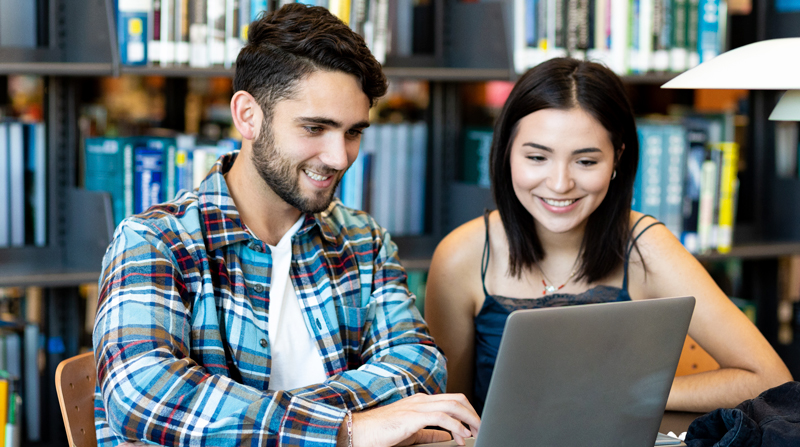 smiling male and female Alamo Colleges students looking at a laptop