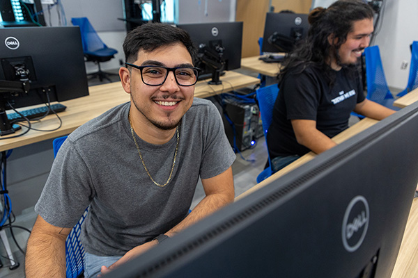 smiling male student using a desktop computer