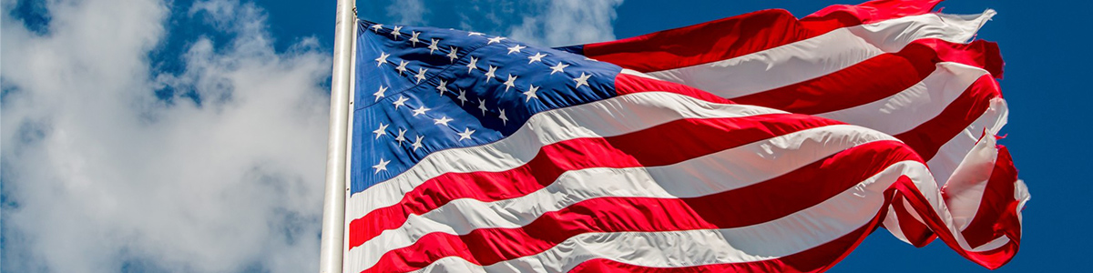 United States Flag waving in front of a clear, blue sky