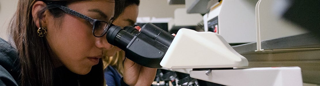 student looking into microscope